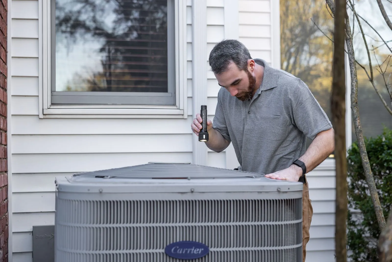 Technicien inspectant une unité de climatisation extérieure